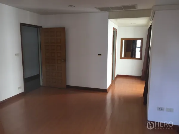 公寓 出租在Pathum Wan, Bangkok - 走廊视角，可见镜面、实木门与复合木地板，通往各房间。