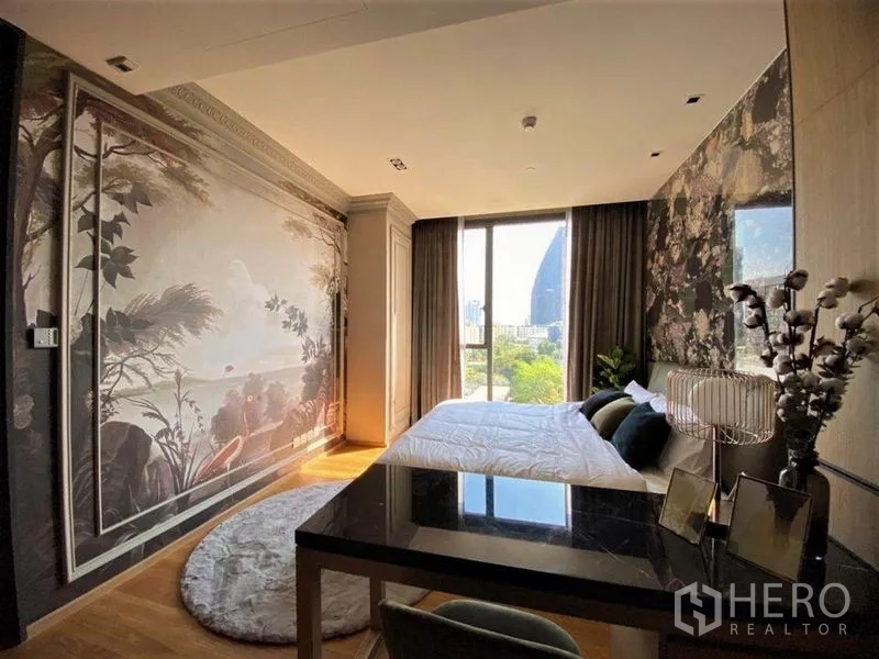 Condominium for rent in Khlong Toei, Bangkok - Bedroom angle showing mural wall, floor-to-ceiling window and greenery outside.