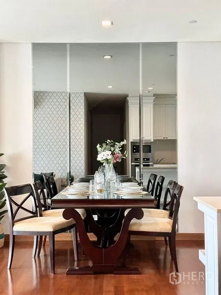 Condominium for rent in Watthana, Bangkok - Formal dining area with six-seat wooden table, place settings, and mirror wall.