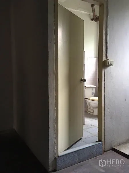 Shophouse for rent in Khlong Toei, Bangkok - Small bathroom doorway showing a toilet and tiled walls.