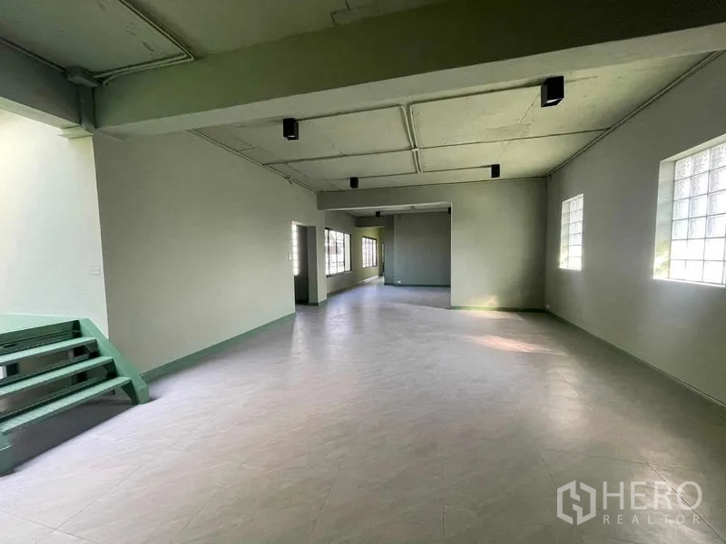 Home Office for rent in Phaya Thai, Bangkok - Spacious open-plan office floor with light green walls, ceiling lights, and side windows.