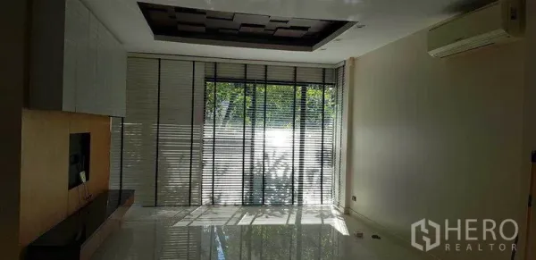 Detached House for rent in Bang Phli, Samut Prakan - Bright living room with floor-to-ceiling windows, blinds, glossy tile floors and a built-in TV wall.