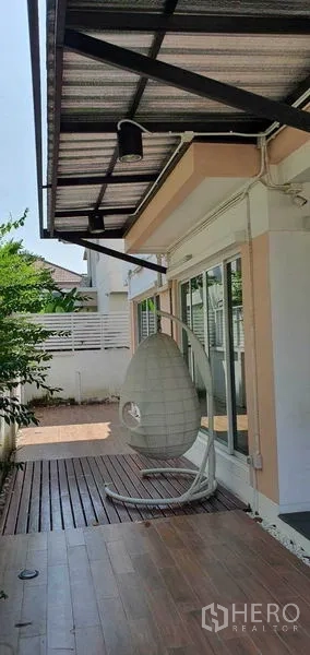Detached House for sale in Khan Na Yao, Bangkok - Side terrace with wood decking, canopy roof and a hanging egg chair.