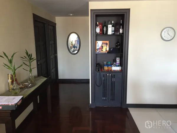 Condominium for rent or sale in Khlong Toei, Bangkok - Entry hallway of Khlong Toei Bangkok condo with dark parquet floor, console table and built-in shelving.