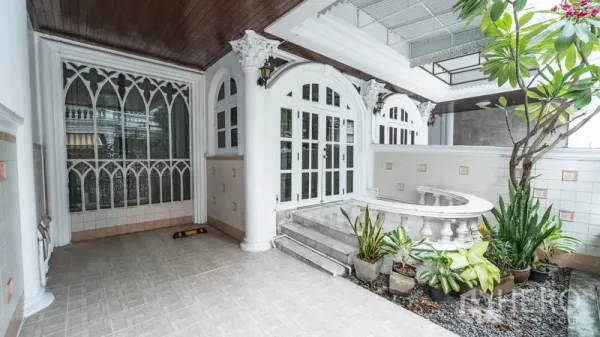 Townhouse for rent in Watthana, Bangkok - Covered front porch and carport with arches, steps, and potted plants.