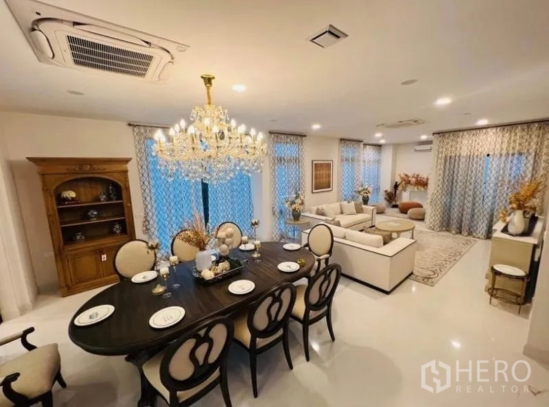 Detached House for rent or sale in Saphan Sung, Bangkok - Open-plan dining and living area featuring a crystal chandelier and large windows.