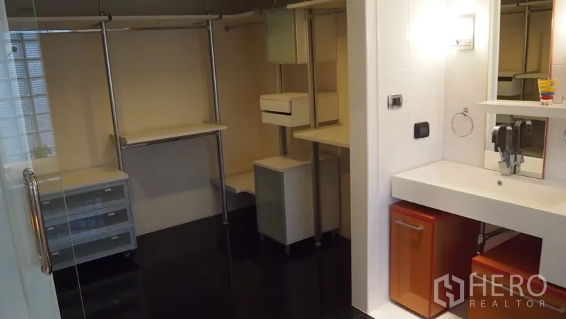Condominium for rent in Khlong Toei, Bangkok - Walk‑in closet and vanity area with open shelving, storage drawers and glass door.