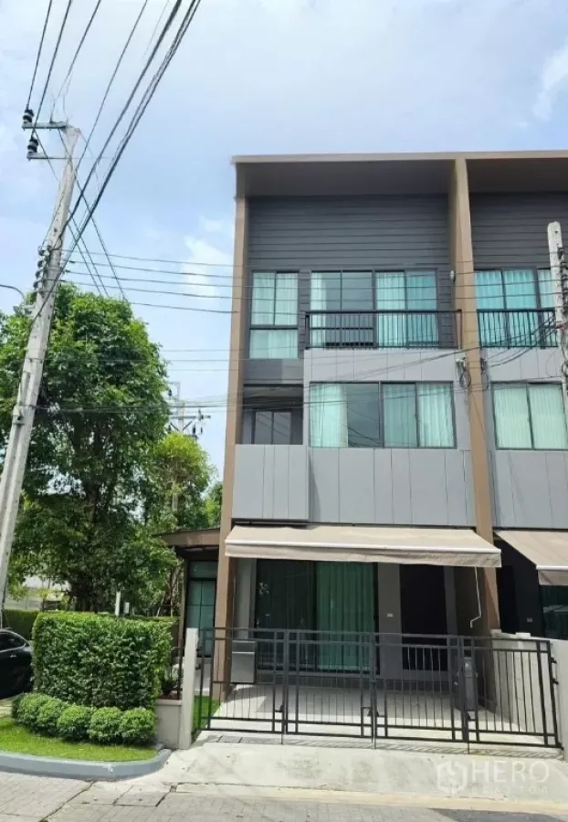 Townhouse for rent in Saphan Sung, Bangkok - Modern three-storey corner townhouse with gated carport and garden frontage.