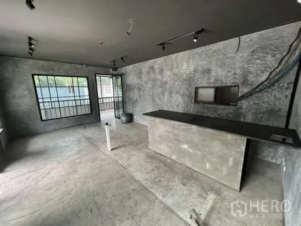 Retail Space for rent in Watthana, Bangkok - Open-plan shop space with concrete finish, large windows and counter ready for fit-out.