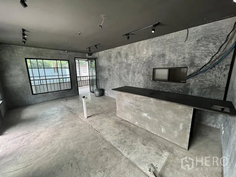 Retail Space for rent in Watthana, Bangkok - Open-plan shop space with concrete finish, large windows and counter ready for fit-out.