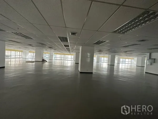 办公空间 出租 - 宽敞的开放式办公室楼层，吊顶、承重柱与大面积落地窗，可欣赏城市景观。