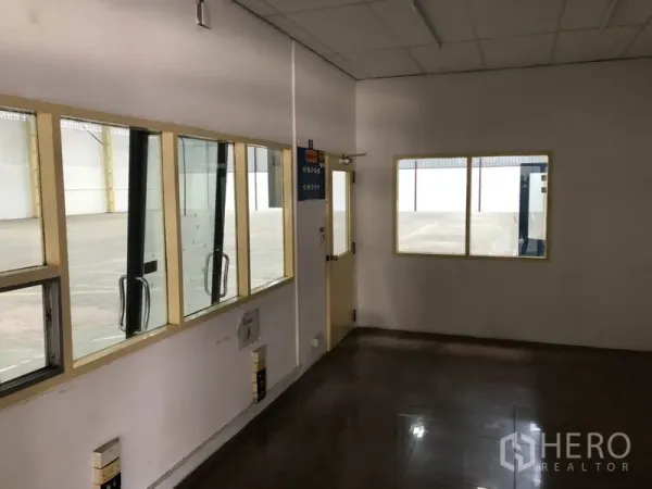 货栈 出租在Mueang Samut Prakan, Samut Prakan - 室内小型办公室，窗户可俯瞰主仓库地面，旁有通往装卸区的门。