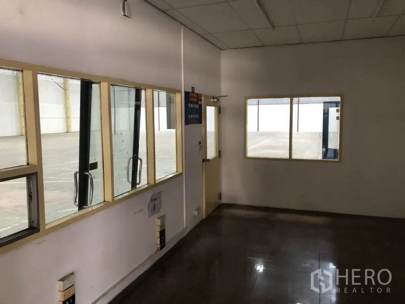 货栈 出租在Mueang Samut Prakan, Samut Prakan - 室内小型办公室，窗户可俯瞰主仓库地面，旁有通往装卸区的门。