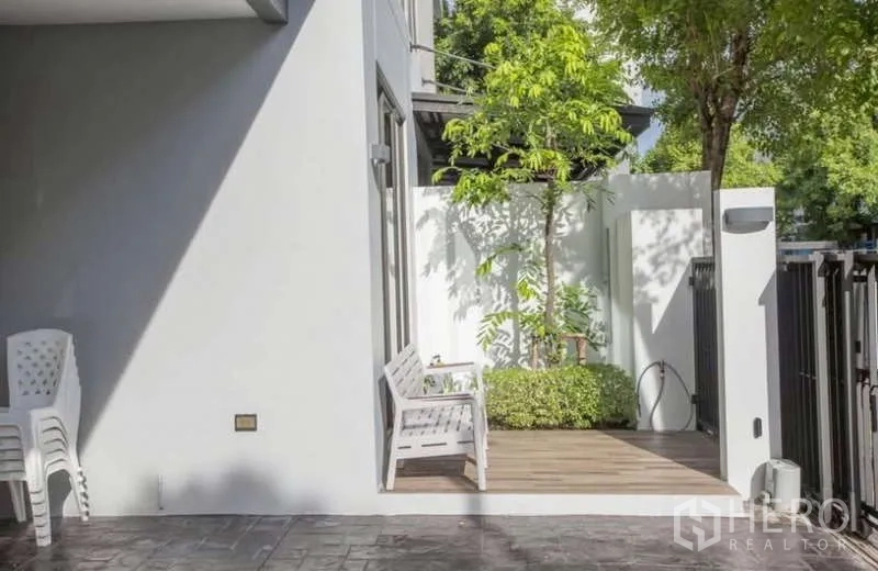 Detached House for rent or sale in Lat Phrao, Bangkok - Small front patio with bench, greenery and private fence by the entry.