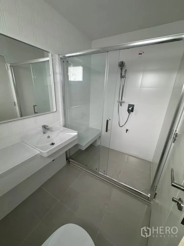 Detached House for rent in Bang Phli, Samut Prakan - Modern bathroom with glass-enclosed shower, white vanity, and large mirror.