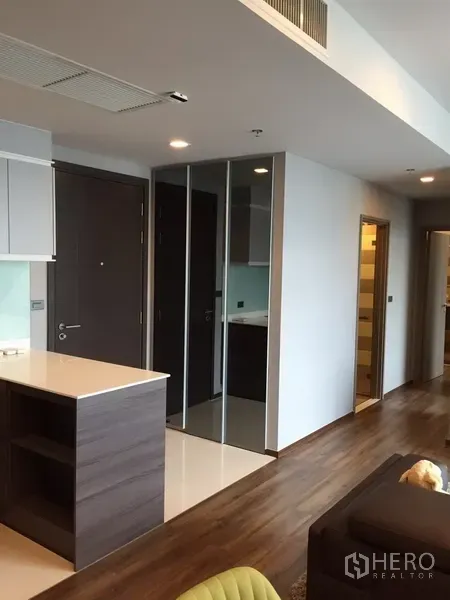 Condominium for rent in Watthana, Bangkok - Entry hallway featuring a built-in mirrored wardrobe, wooden flooring, and recessed lighting.