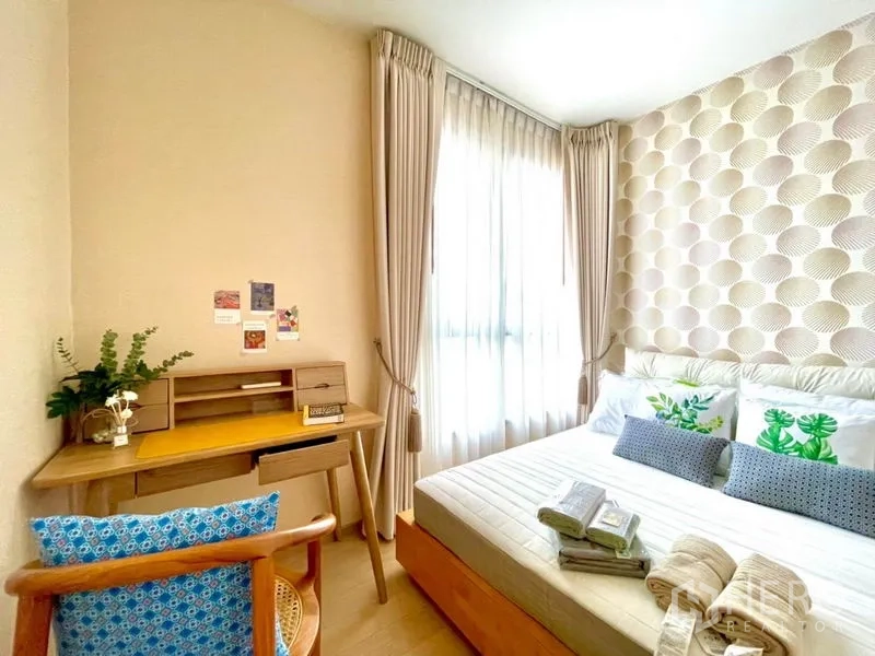 Condominium for rent or sale in Watthana, Bangkok - Cozy second bedroom with desk by a large window and textured geometric wallpaper.
