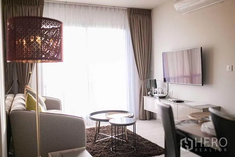 公寓 出租在Pathum Wan, Bangkok - 起居区，电视柜、圆形茶几与薄纱窗帘。