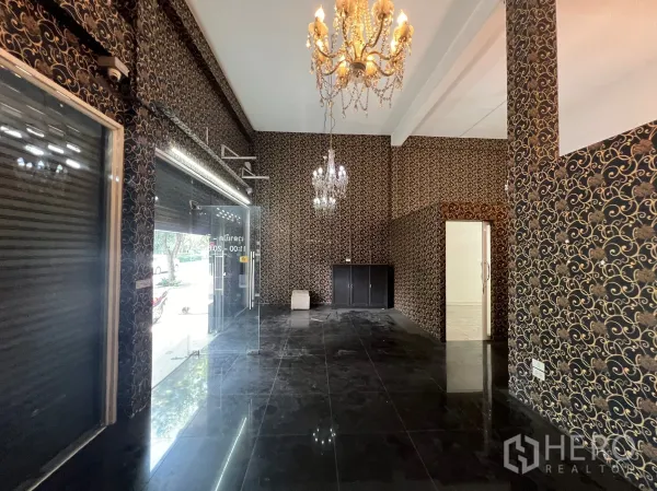 Shophouse for rent in Khlong Toei, Bangkok - Ground-floor showroom with glass frontage, black tile floors and chandelier lighting.