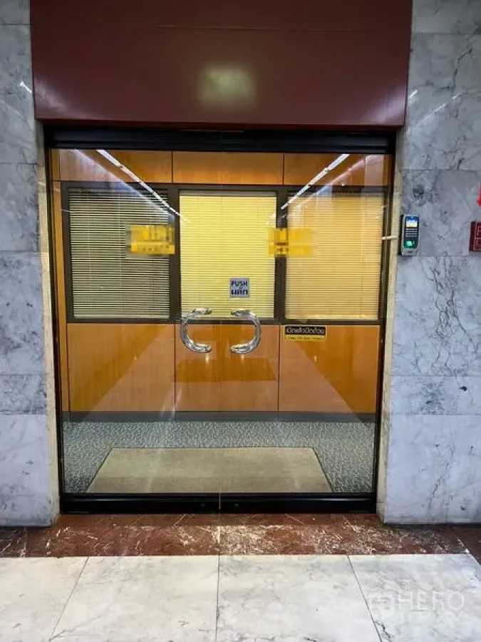 Office Space for rent - Glass double-door office entrance in a marble corridor with access control panel.