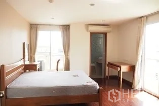 Condominium for rent in Pathum Wan, Bangkok - Master bedroom with wooden bed, desk, large windows and ensuite door.
