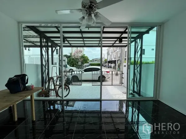 Townhouse for sale in Bang Kapi, Bangkok - Glass-enclosed front room with sliding doors opening to a covered carport.