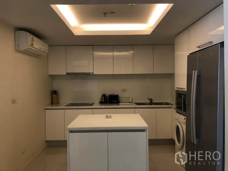 公寓 出租在Pathum Wan, Bangkok - 现代白色厨房，带中岛、高柜、冰箱与洗衣机。