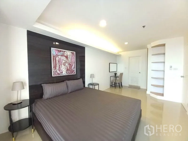 Condominium for rent in Khlong Toei, Bangkok - Spacious master bedroom with large bed, lamps and study area.