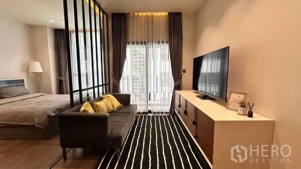 Condominium for rent in Watthana, Bangkok - Living room facing the balcony with glass divider to the bedroom and a striped area rug.