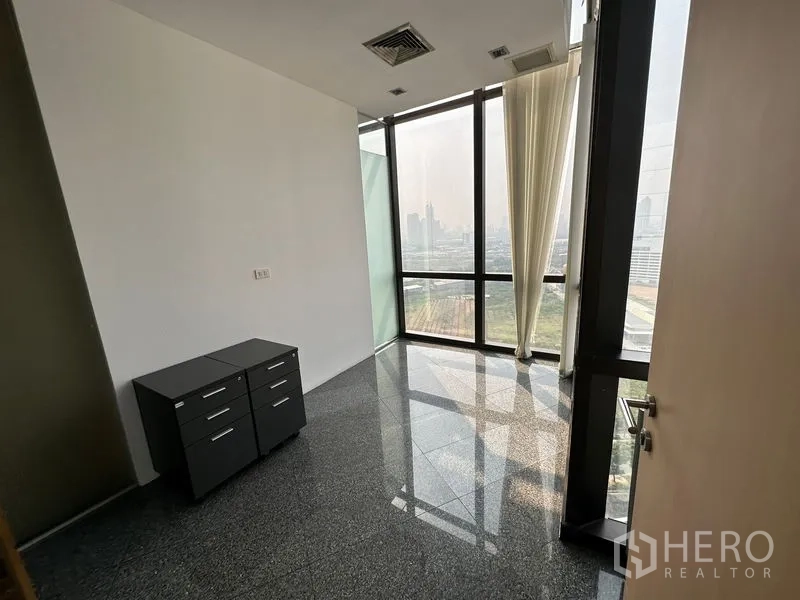 Office Space for rent - Corner office with floor-to-ceiling windows, sheer curtains, city views and polished stone floors.