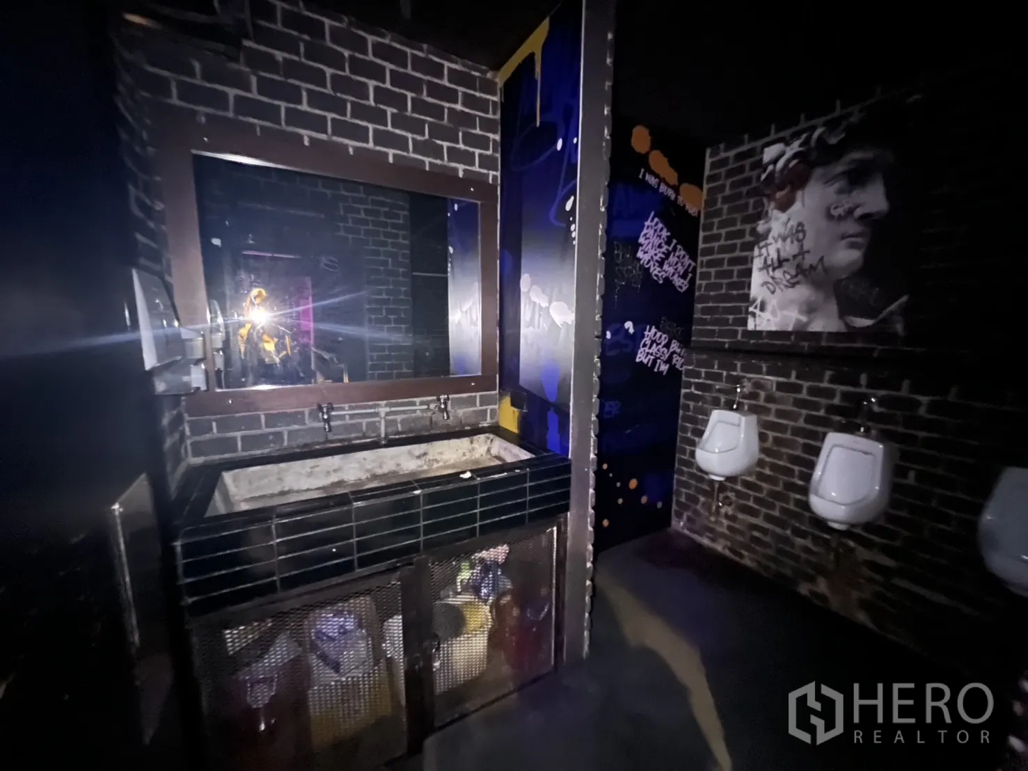 Retail Space for rent in Bangkok - Industrial men’s restroom with brick walls, urinals and large mirror.