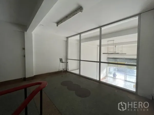 Shophouse for rent in Phra Khanong, Bangkok - Mezzanine office area with large interior glass window overlooking the front retail space.