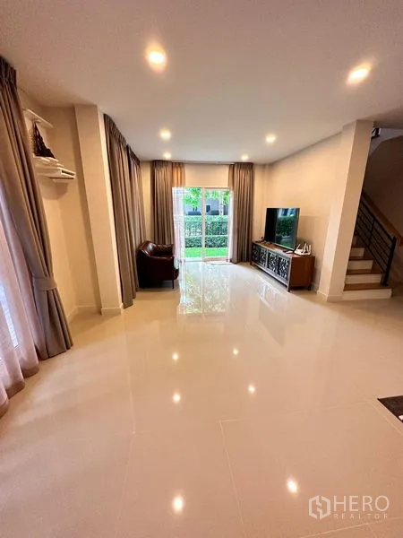 独立式住宅 出售在Prawet, Bangkok - 客厅光亮瓷砖地面，电视柜与通往花园的推拉门。