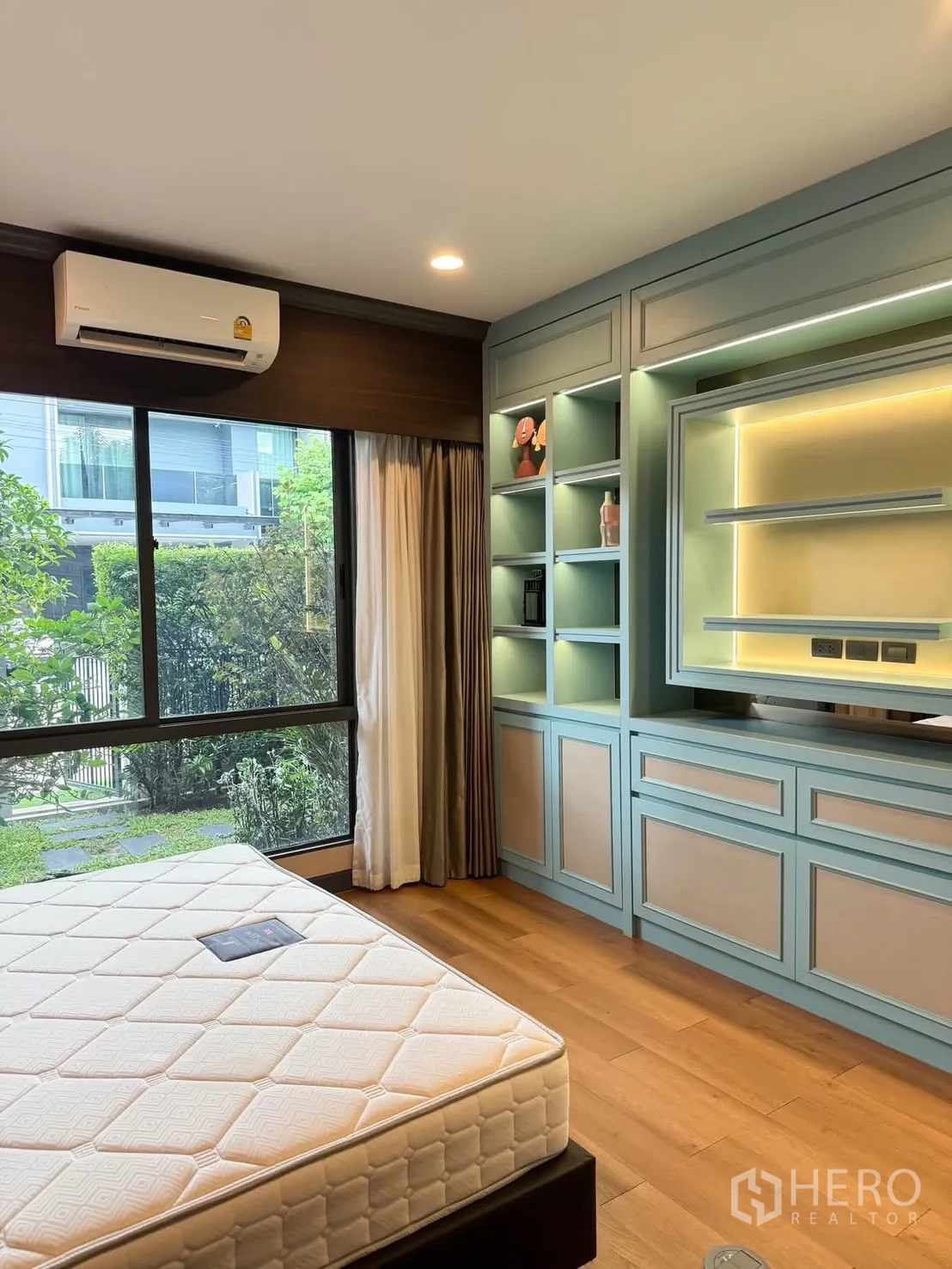 Detached House for rent in Bang Kapi, Bangkok - Bedroom with large window, mint built-in cabinetry and shelving, and garden view.