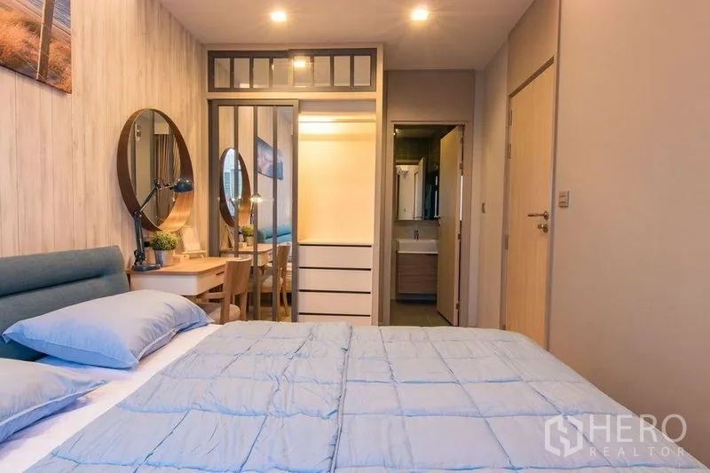 Condominium for sale in Watthana, Bangkok - Bedroom view toward mirrored closet, dressing table and bathroom entrance.