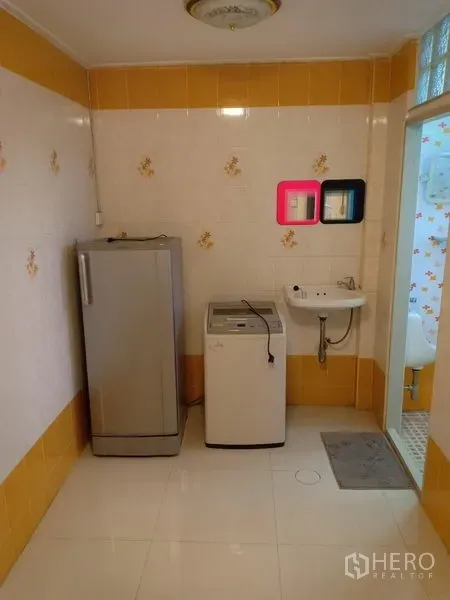 Townhouse for rent in Phra Khanong, Bangkok - Utility room with refrigerator, washing machine and wall-mounted sink beside a bathroom door.