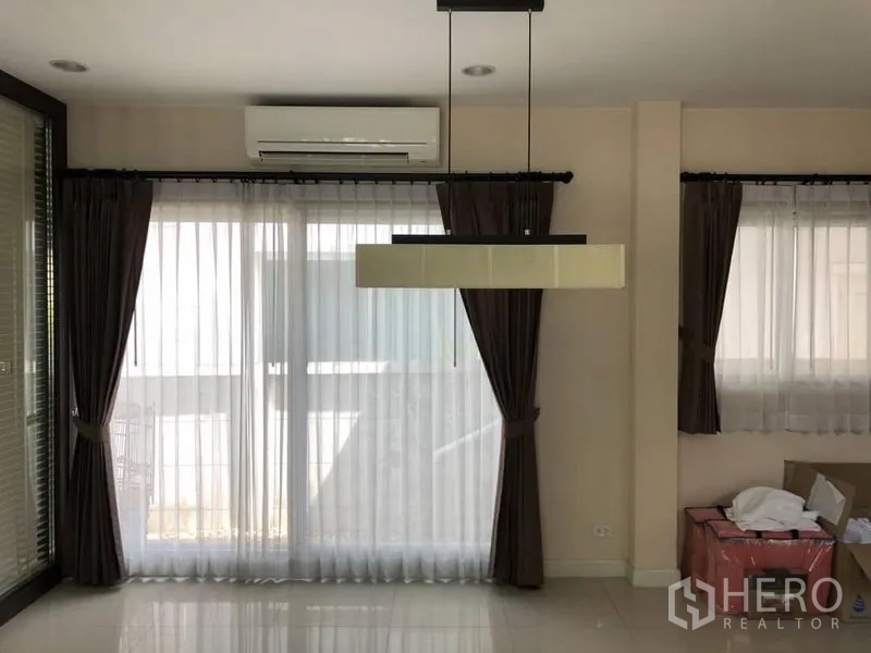 Detached House for rent in Saphan Sung, Bangkok - Dining area with pendant light, floor-to-ceiling windows, sheer curtains and air conditioning.