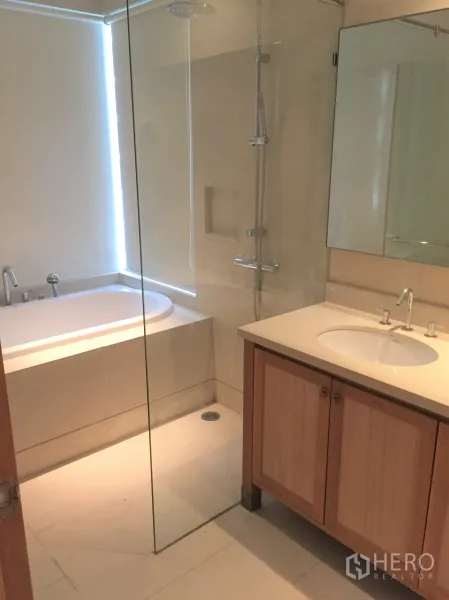Condominium for rent in Khlong Toei, Bangkok - Contemporary bathroom featuring a glass-enclosed shower, bathtub and vanity sink.