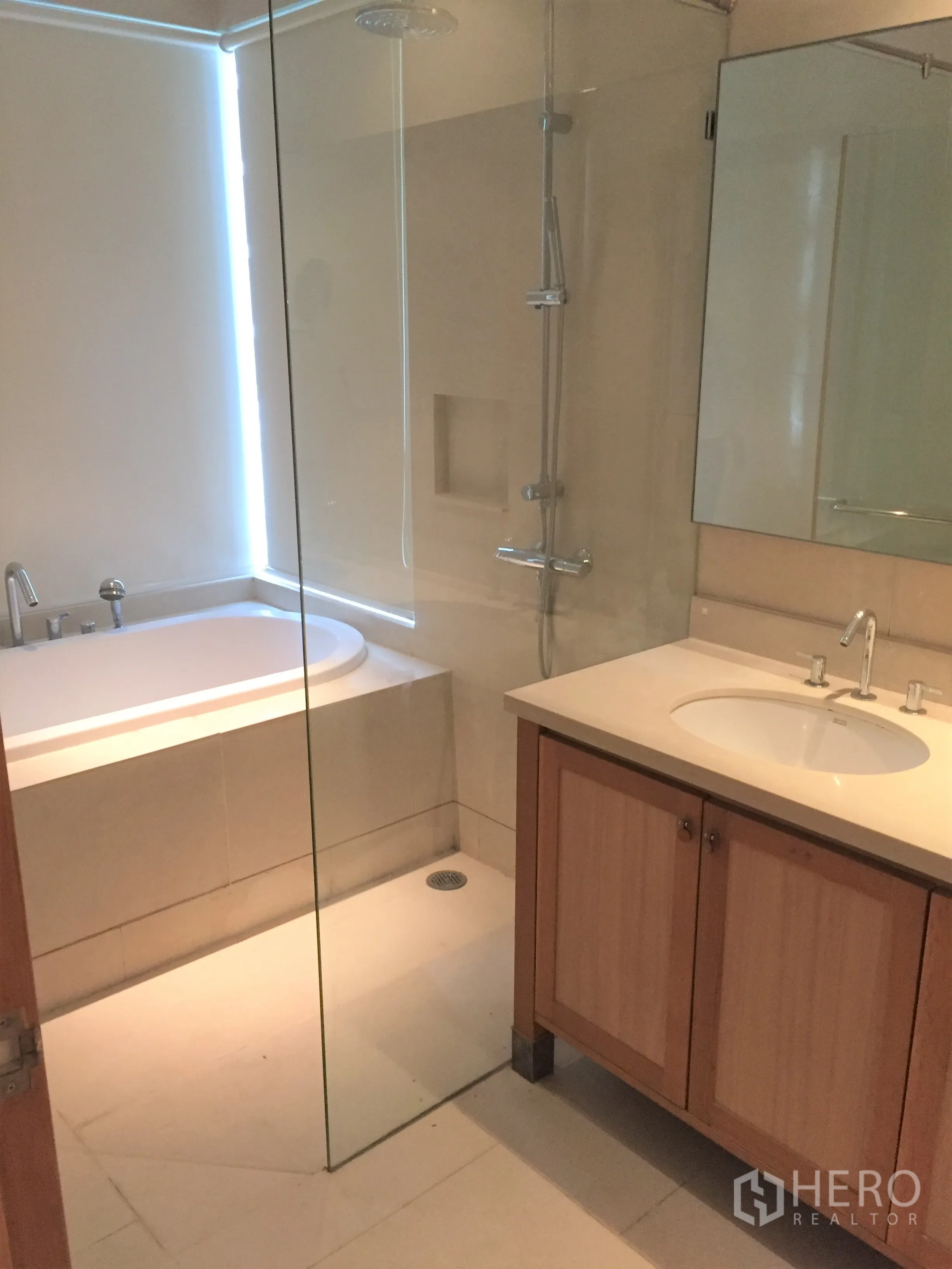 Condominium for rent in Khlong Toei, Bangkok - Contemporary bathroom featuring a glass-enclosed shower, bathtub and vanity sink.