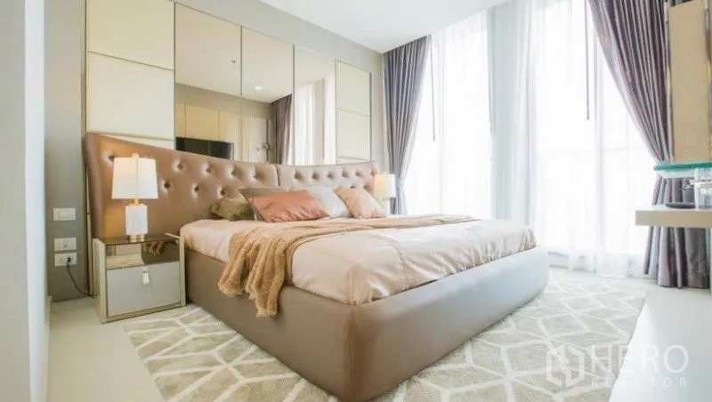 Condominium for rent in Pathum Wan, Bangkok - Bright master bedroom with tufted headboard, soft rug and sheer-draped windows.