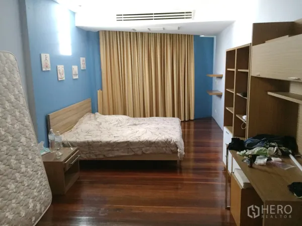 联排别墅 出租在Khlong Toei, Bangkok - 宽敞卧室，木地板、蓝色点缀墙、内置搁架与遮光窗帘。