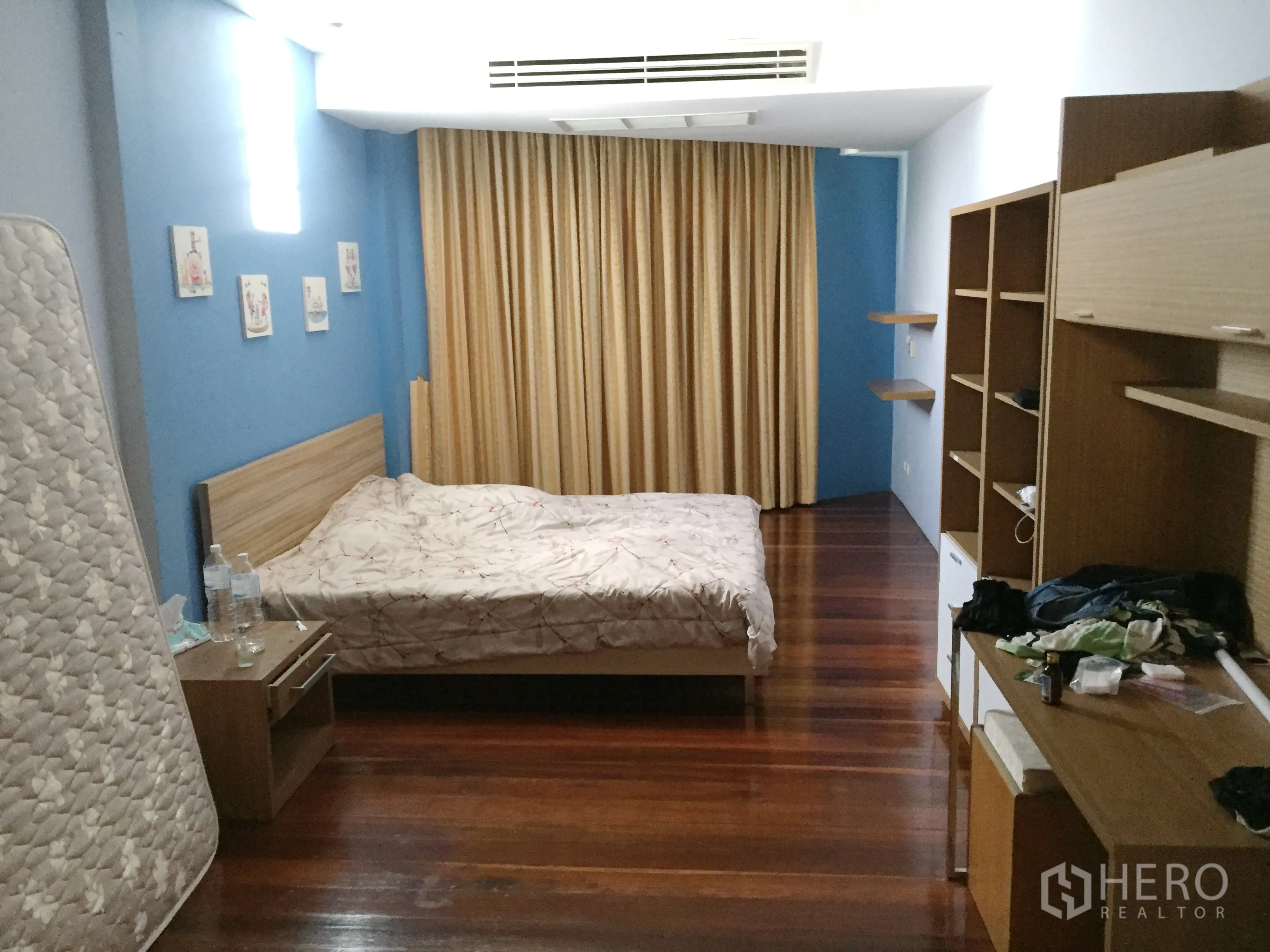 联排别墅 出租在Khlong Toei, Bangkok - 宽敞卧室，木地板、蓝色点缀墙、内置搁架与遮光窗帘。