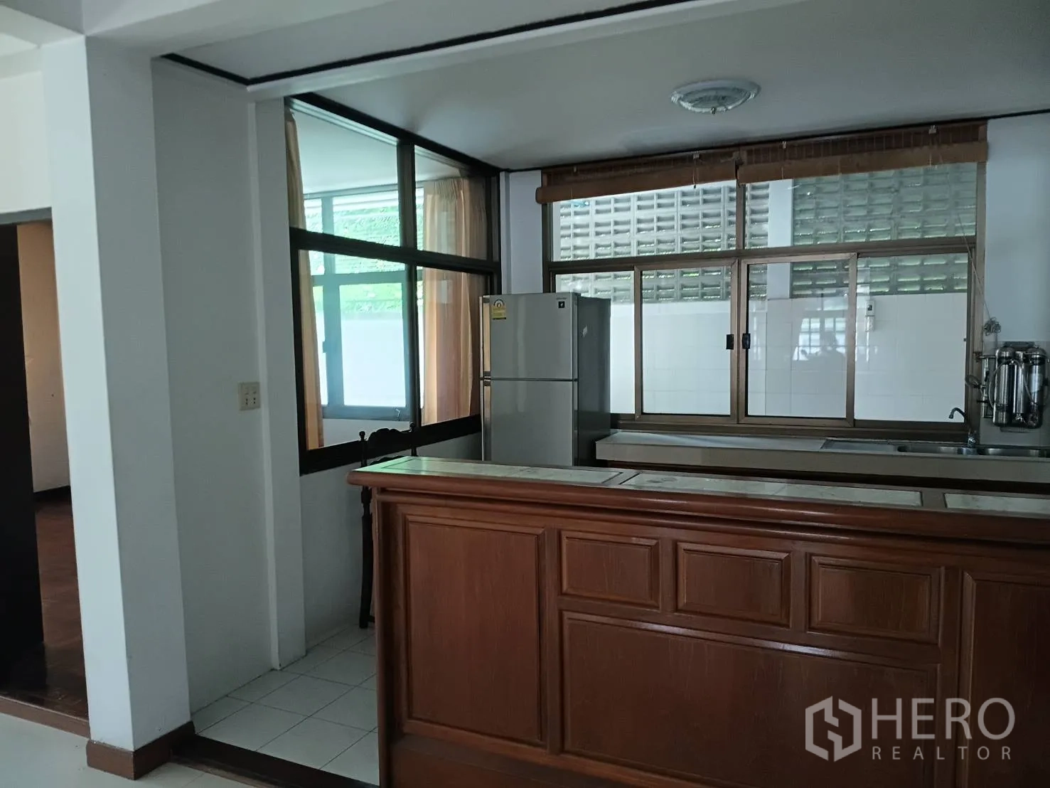 独栋房屋 for sale in Watthana, Bangkok - 厨房一角，带木质吧台、窗户与冰箱。