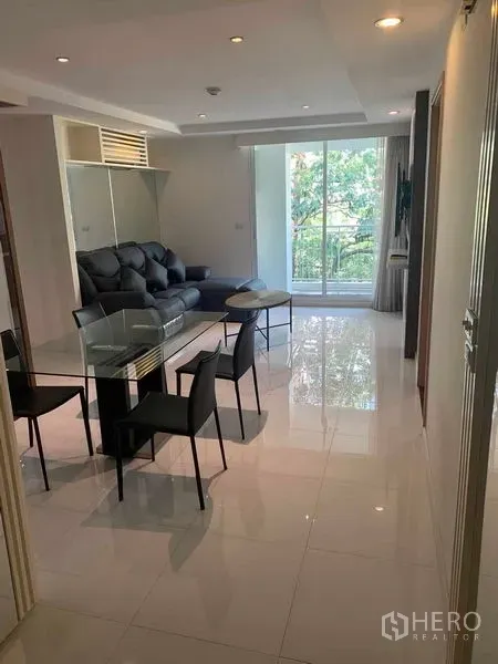Condominium for rent or sale in Khlong Toei, Bangkok - Bright living and dining area with glass table, sofa, and sliding doors to the balcony.