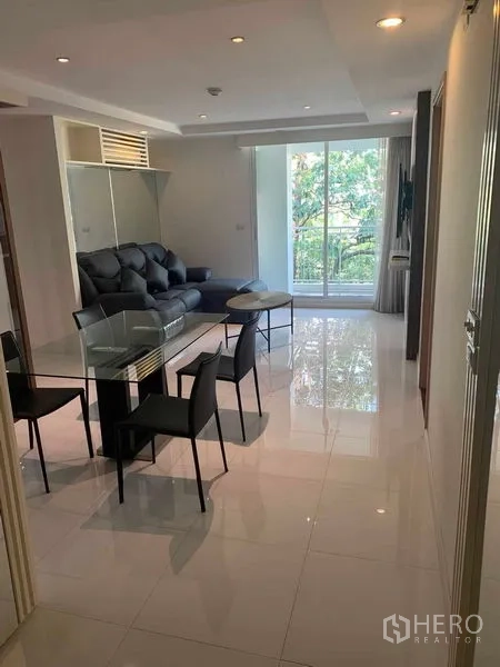Condominium for rent or sale in Khlong Toei, Bangkok - Bright living and dining area with glass table, sofa, and sliding doors to the balcony.