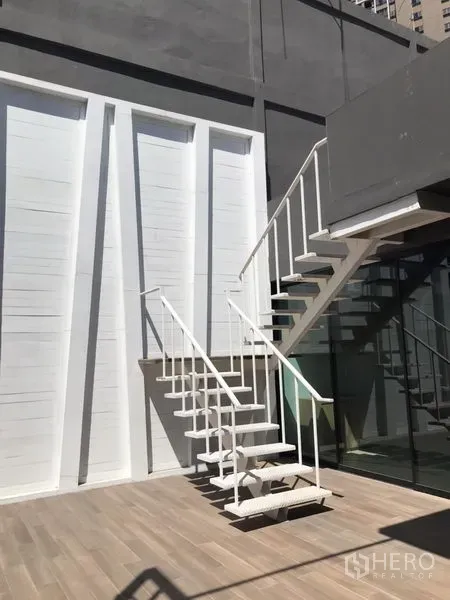 Retail Space for rent in Khlong Toei, Bangkok - Exterior courtyard with white metal staircase and glass facade leading to the upper level of the retail unit.