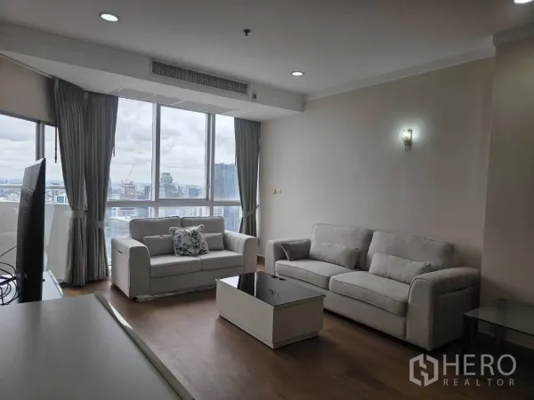 公寓 出租在Khlong Toei, Bangkok - 客厅采光充足，双灰色沙发与茶几，落地窗眺望曼谷天际线。