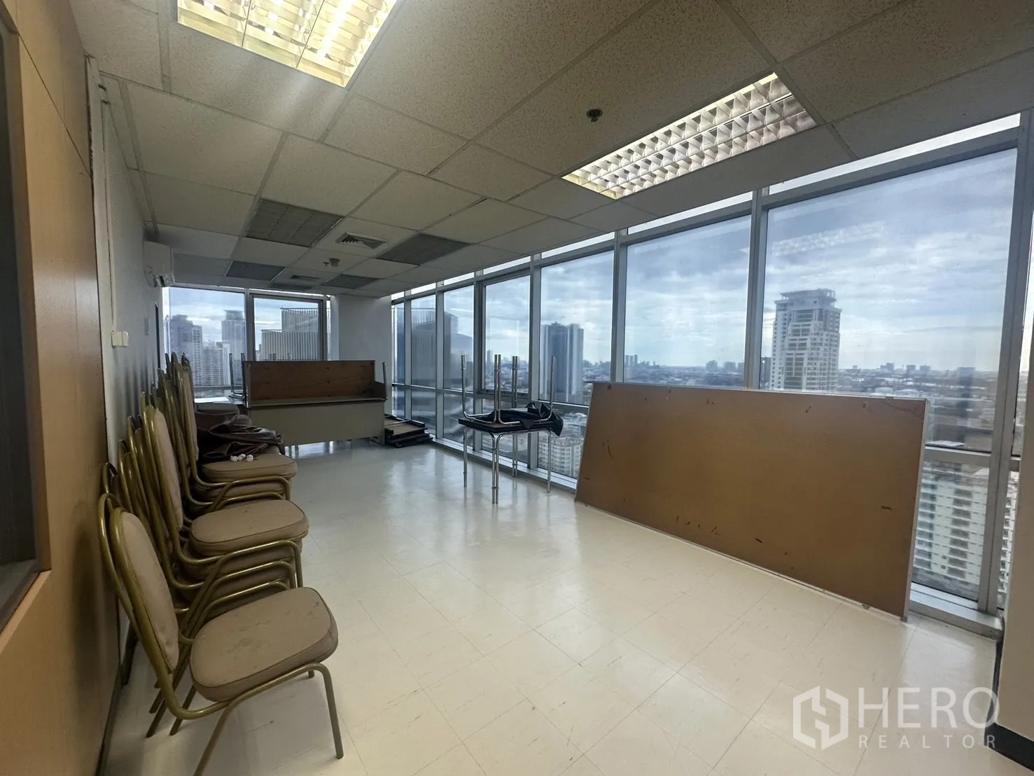 Office Space for rent - Auxiliary room beside the window wall with stacked chairs and wide skyline outlook.