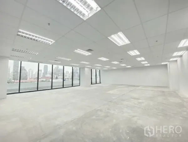 Office Space for rent in Ratchathewi, Bangkok - Bright open-plan office interior with grid ceiling, LED lights, concrete floor and full-height windows overlooking Bangkok.