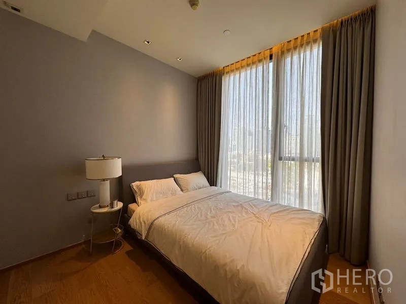 Condominium for rent - Second bedroom with double bed and tall windows showing city outlook.
